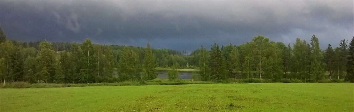 Vihertävät Mannilan pellot ja tumma taivas